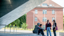 Studierende unterhalten sich vor dem Zentralgebäude