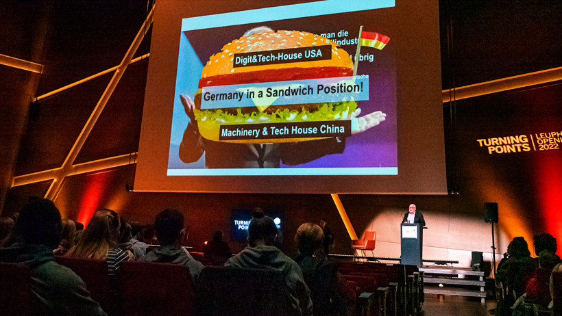 Thomas Sattelberger steht auf der Bühne des Auditoriums