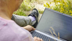 Mann mit Laptop im Grünen_over_the_shoulder_close