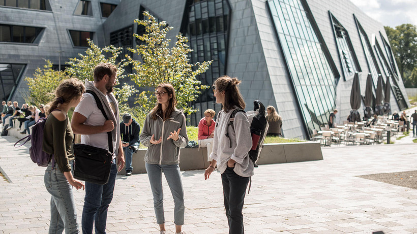 Gruppe von Studierenden im Gespräch vor dem Zentralgebäude der Leuphana Universität 