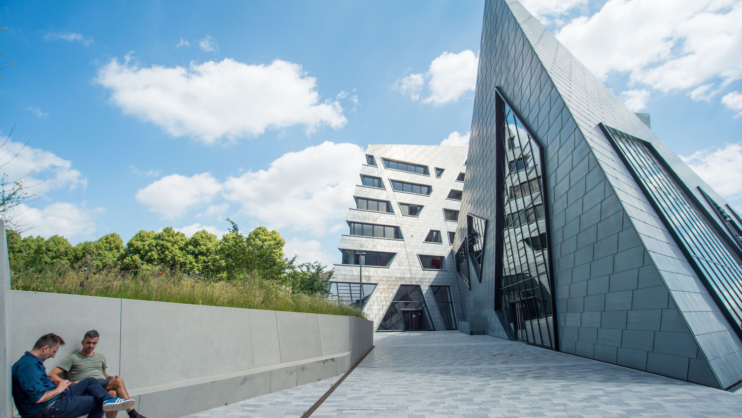 Mitarbeitende der Universität vor dem Zentralgebäude Mitarbeitende der Universität sitzen am Vorplatz des Zentralgebäudes der Leuphana.