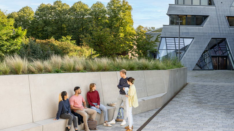 Master's students from the Master's programme Cultural Studies are talking in front of the central building