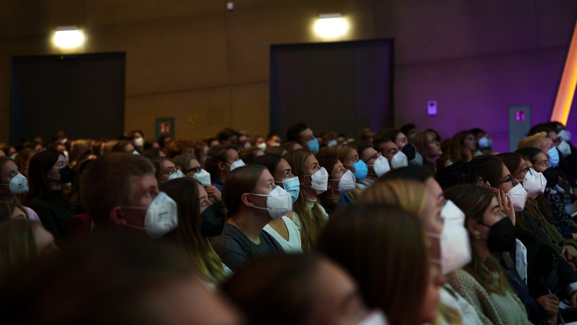 Viele junge Menschen sitzen mit Mundschutz im Auditorium