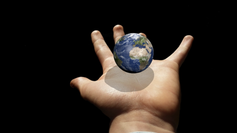 Der Planet Erde schwebt über einer ausgebreiteten, menschlichen Hand.