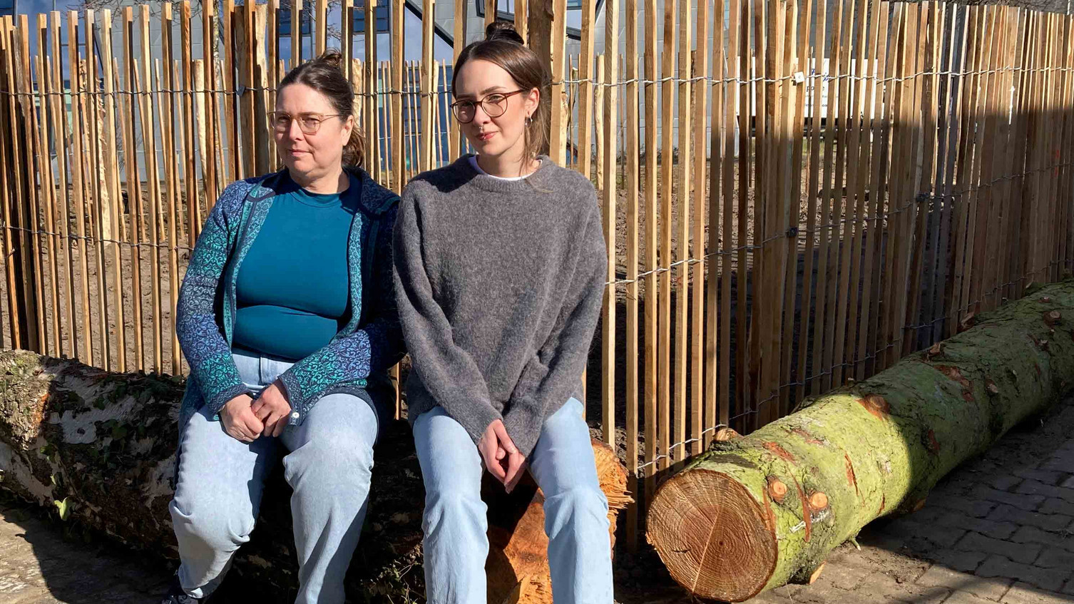 Two educators sitting in front of the fenced CampusAckerdemie plot