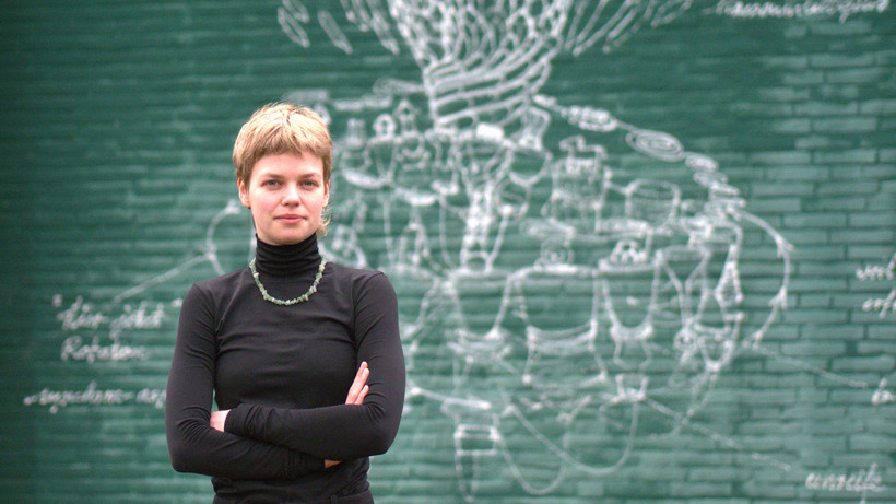 Portraitfoto von Chiara Welter, Studentin des Masters Kritik der Gegenwart, vor einem Mural an der Außenwand eines Hörsaals der Leuphana