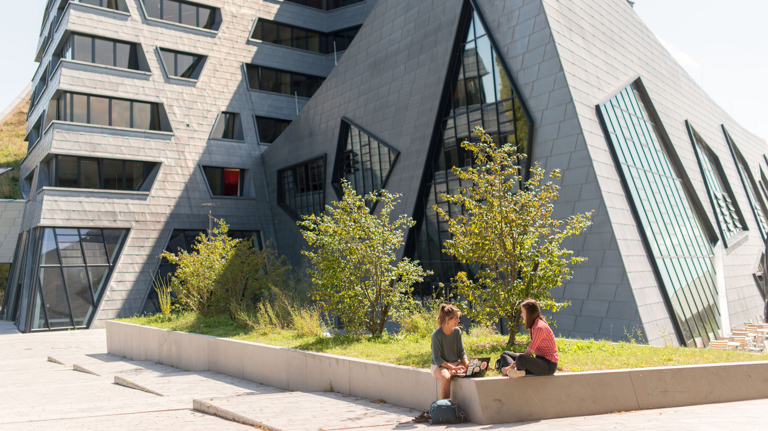 Students Greenery Central Building Leuphana Sustainability Science: Entrepreneurship, Agency and Leadership Two students sitting in the greenery in front of Leuphana's central building.