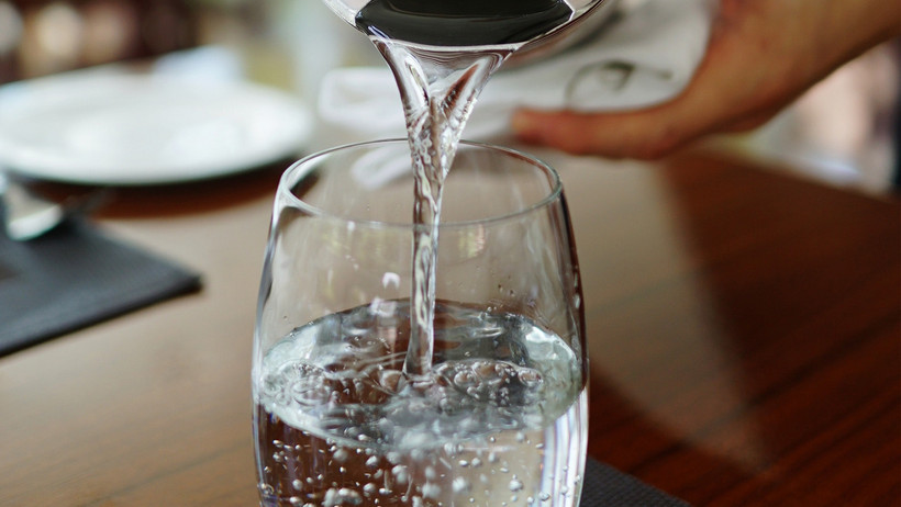 Wasser wird in ein Glas gegossen.