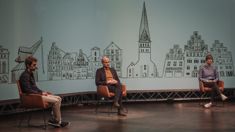 Von Links: Finn Reinhardt, Daniel Lang und Kristin Jordan auf der Bühne des Leuphana Studios.