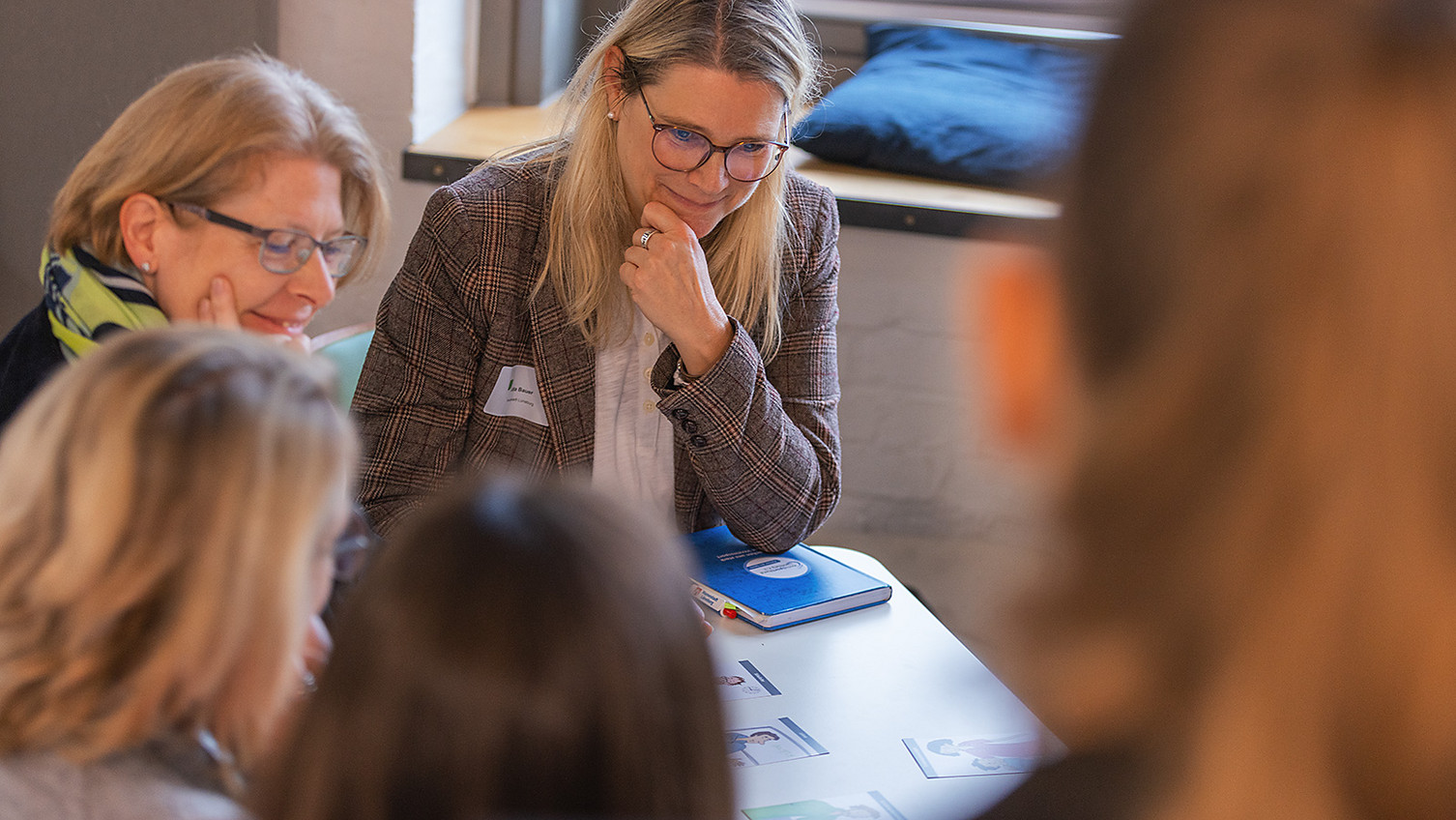 Vier Frauen sitzen an einem Tisch. Darauf liegen Arbeitsmaterialien.