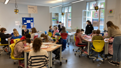 Das Bild zeigt Studierende, die Schüler*innen bei der Erforschung ihrer Fragen in der Leuphana Lernwerkstatt Lüneburg unterstützen.
