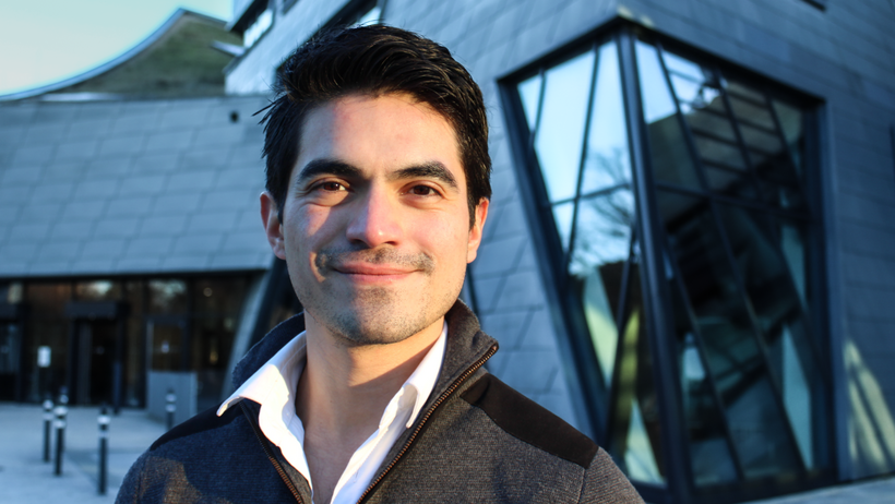 Portrait oif Fernando Aguilera, student of the Management & Sustainanble Accounting and Finance Masters programme, in front of Leuphana University's central building.