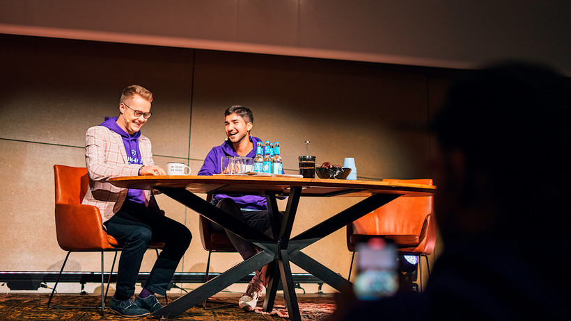 Der Moderator und ein Gast lachen gemeinsam auf der Bühne des Auditoriums