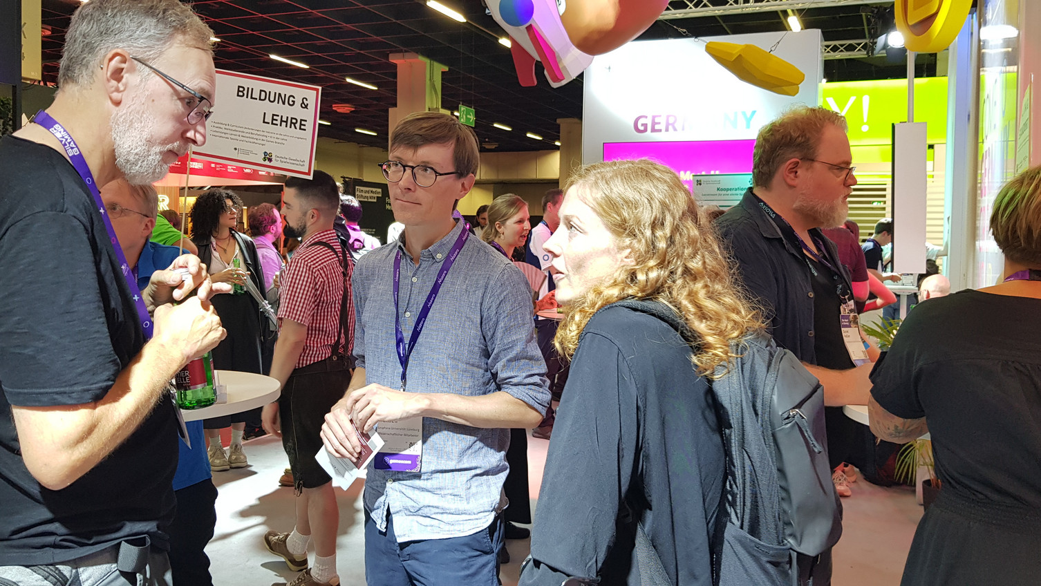 Zwei Mitarbeitende der Leuphana Innovation Community Schulentwicklung und Leadership im Gespräch mit einer Person auf der Spielemesse Gamescom.