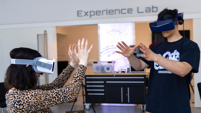 Zwei Studierende mit VR-Brillen, die diese vor dem Experience Lab selbst ausprobieren