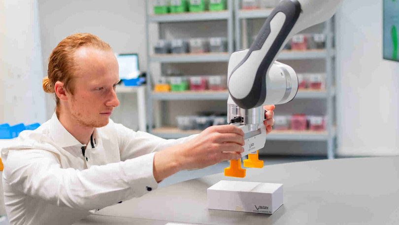 Forschender mit Roboterarm