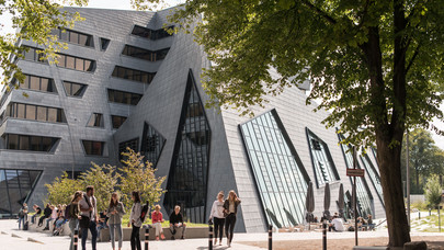 Studierende vor dem Zentralgebäude der Leuphana Universität Lüneburg unterhalten sich und machen Pause