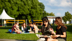 Studierende sitzen auf der Mensawiese und unterhalten sich