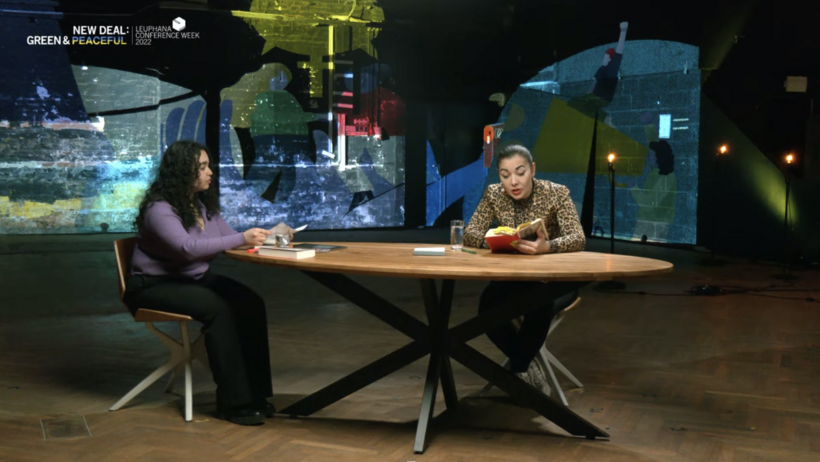 Die Moderatorin des Talks (links) und Reyhan Şahin (rechts) sitzen an einem Tisch, während Şahin aus ihrem Buch vorliest.