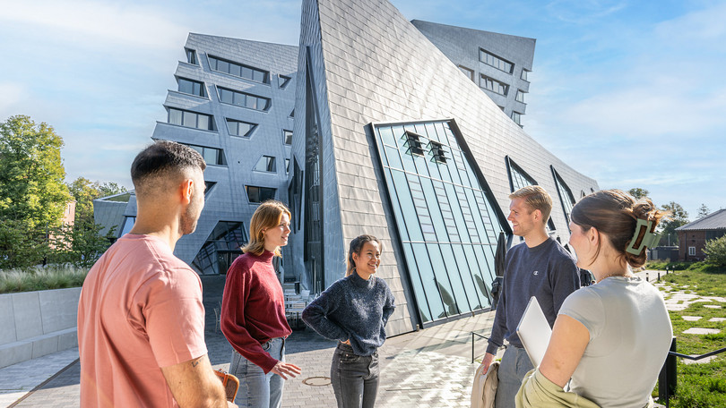 Gruppe von Studierenden (Master Management) im Gespräch vor dem Zentralgebäude der Leuphana.