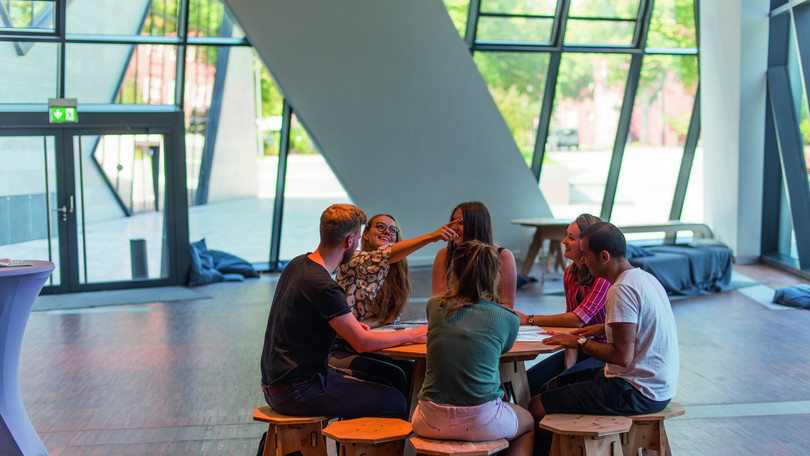 Gruppenarbeit im Zentralgebäude Studierende bei einer Gruppenarbeit an einem runden Tisch im Zentralgebäude der Leuphana