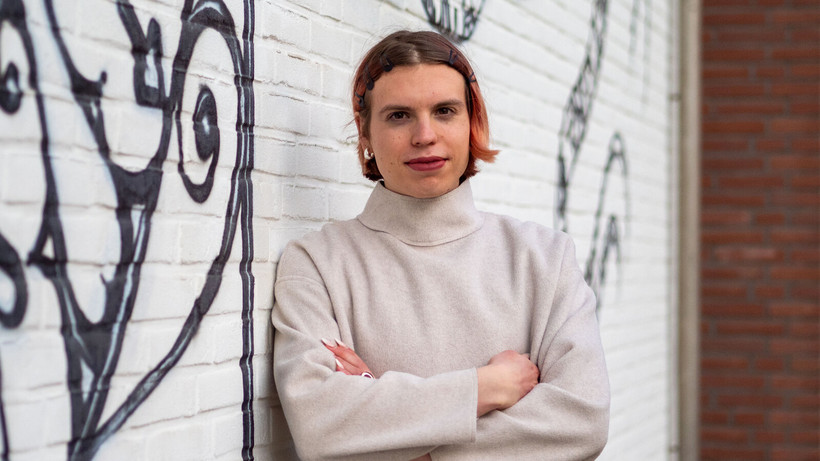 Portrait photo of Nike Mattheis, student of the Masters Critical Studies, in front of a mural on the outside wall of a lecture hall of Leuphana.